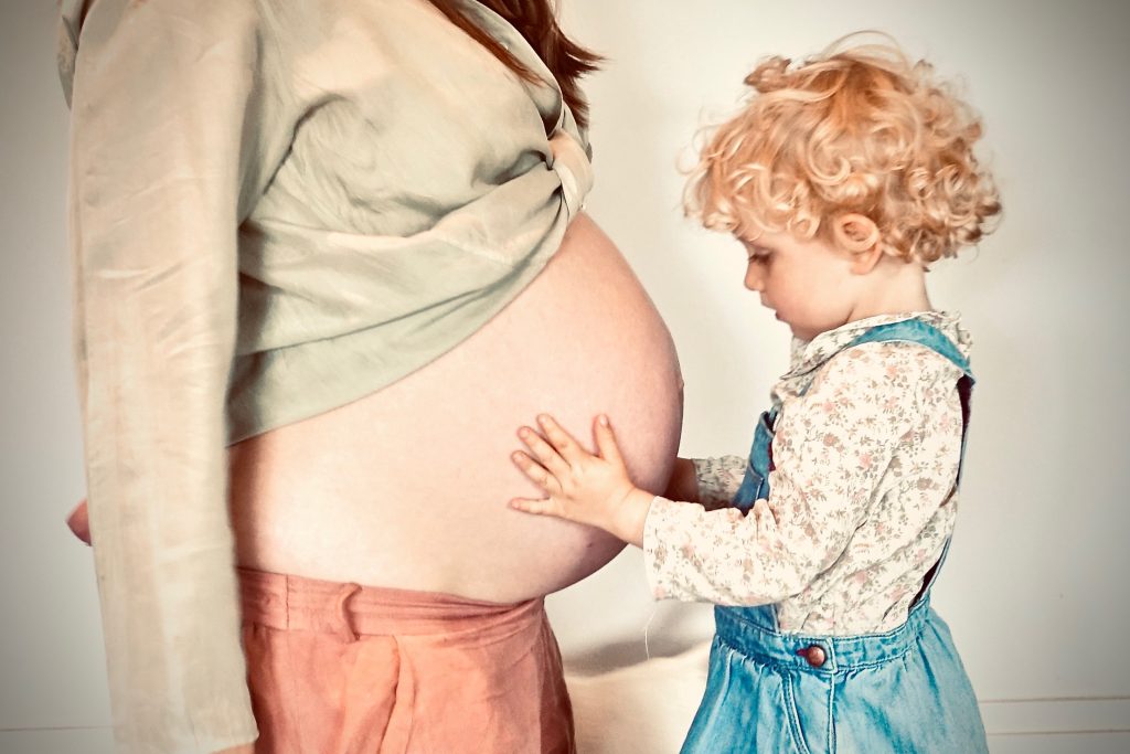 Expertenwissen zur Ernährung in der Schwangerschaft - Kind das staunend den Bauch einer schwangeren Frau berührt